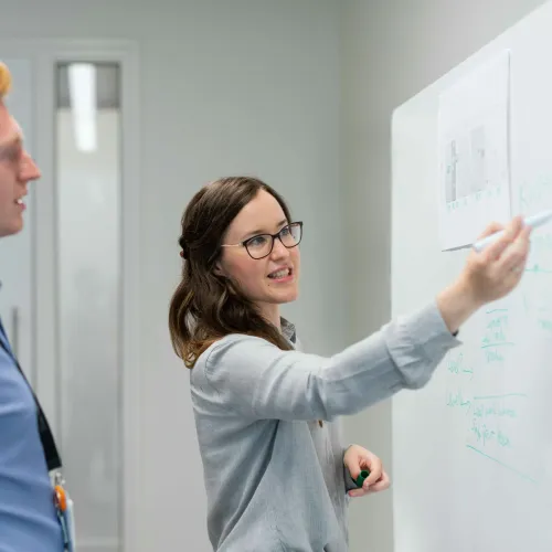 a man and a woman writing on a whiteboard