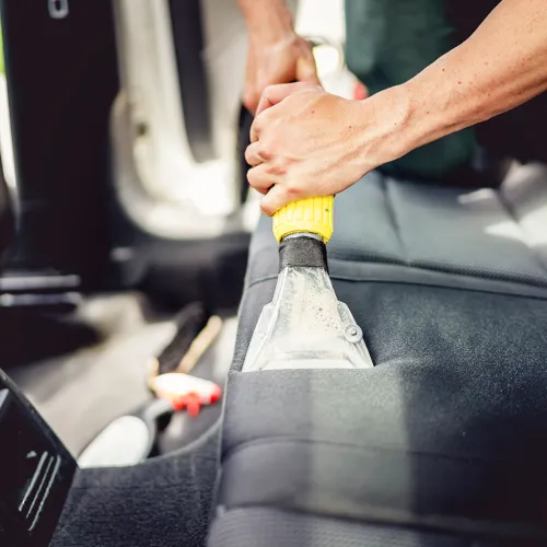 a person holding a yellow car seat vacuum