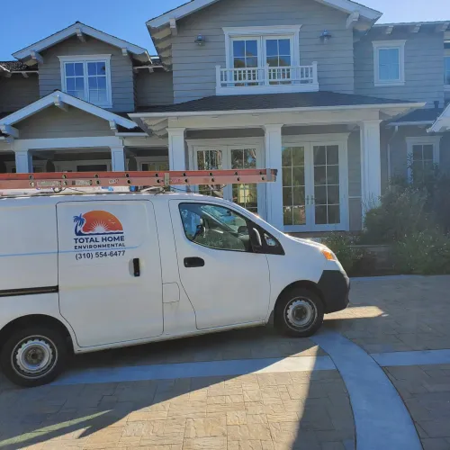 White service van with ladder parked in front of modern suburban house on a sunny day