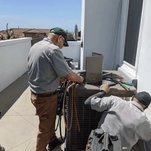 Two HVAC technicians working outdoors on an air conditioning unit near a house on a sunny day.