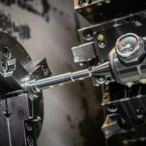 Close-up of a CNC lathe machine precisely machining a metal rod with sharp cutting tool.