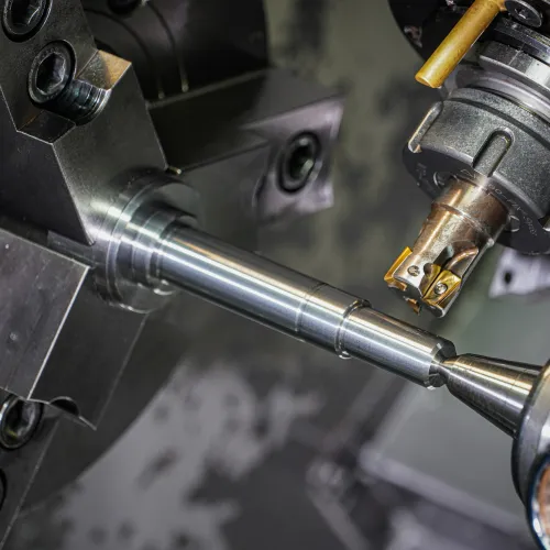 CNC lathe machine machining a metal shaft with precision cutting tools in a modern factory.