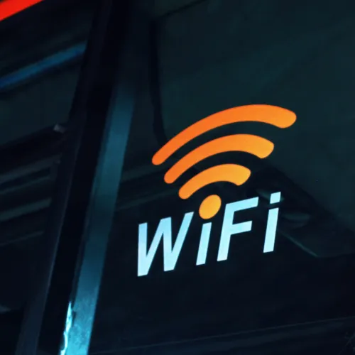 WiFi symbol and text in orange and white on a dark glass surface, likely on public transport or a window.