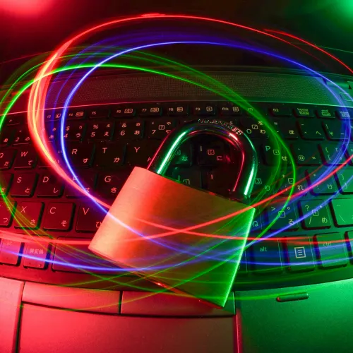 Padlock on laptop keyboard with swirling red, green, and blue light trails symbolizing cybersecurity and data protection.