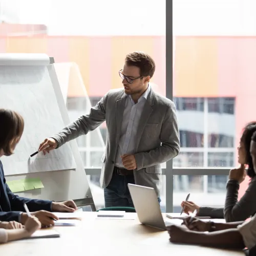 Businessman giving presentation with flip chart to colleagues in modern office meeting room