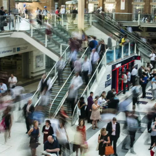 Busy London underground station with blurred crowd moving around escalators and waiting areas.