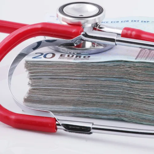 Stack of 20 euro banknotes with a red and silver stethoscope on top symbolizing healthcare costs.