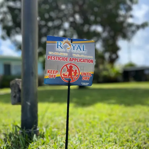 Royal Pest & Termite sign warns of pesticide application with instructions to keep off until dry on green lawn.