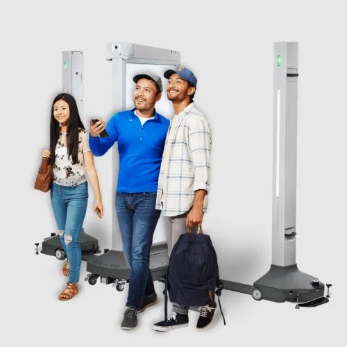 Three diverse young adults smiling and posing with advanced security metal detectors on wheels against a plain background