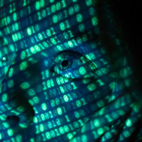 Close-up of a human face overlaid with glowing green binary code representing digital technology and data.