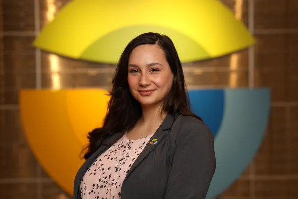 Professional woman in gray blazer standing against colorful geometric background.