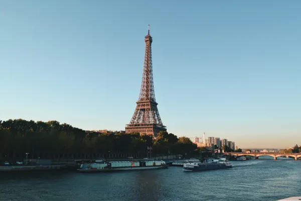 boats floating down the river in front of the Eiffel Tower