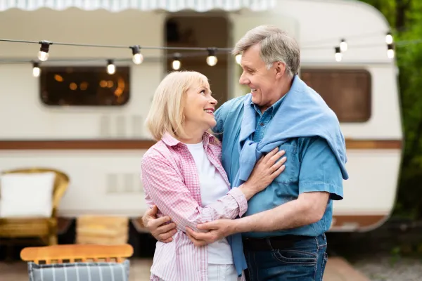 an elderly couple standing in front of an old RV