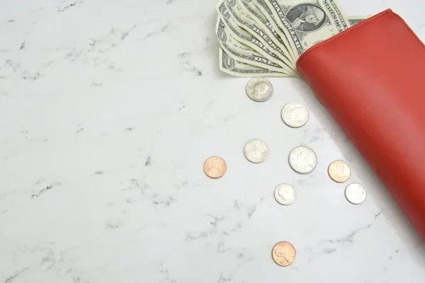 a red wallet with dollar bills and coins spilling out