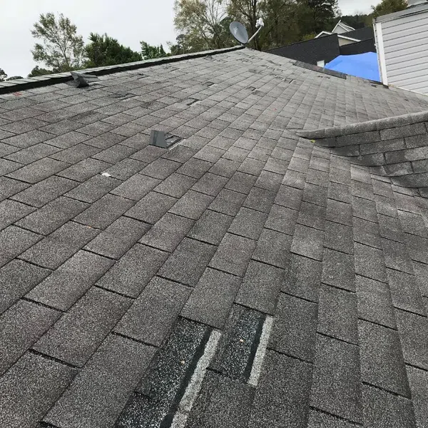 Close-up of a shingle roof showing wear, missing shingles, and areas needing repair.