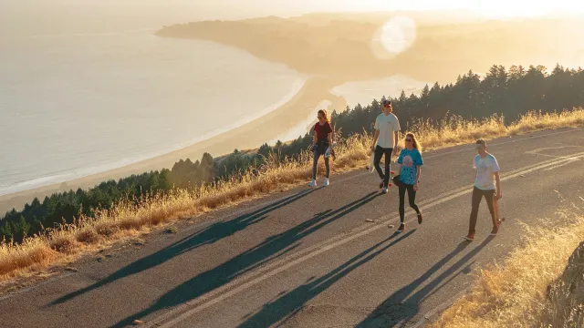 a group of people walking on a road by a body of water
