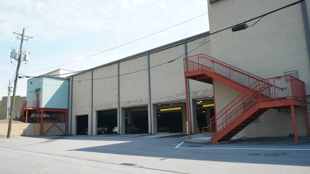Urban commercial building with multiple garage bays and red exterior staircases under clear sky.
