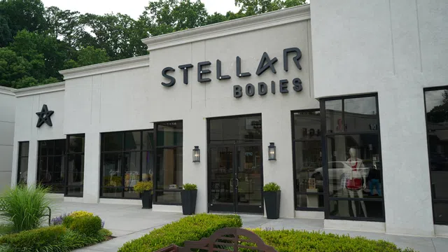 Exterior view of Stellar Bodies fitness studio with modern signage and large windows surrounded by greenery