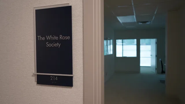 Office door sign for The White Rose Society, room 214, with a dimly lit hallway and office visible inside.
