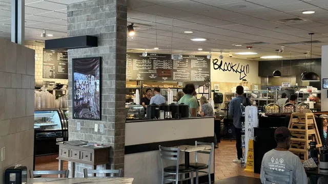 Busy Brooklyn cafe interior with customers, menu boards, modern decor, and seating area with tables and chairs.