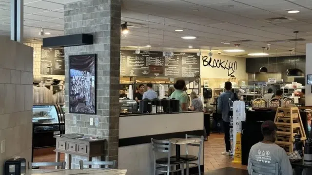Interior view of a busy Brooklyn café with customers, menu boards, and seating areas.
