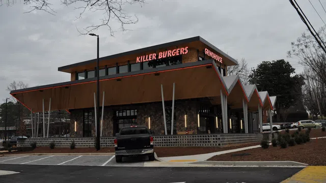 Modern Killer Burgers Grindhouse restaurant with unique angular roof and outdoor lighting at dusk.