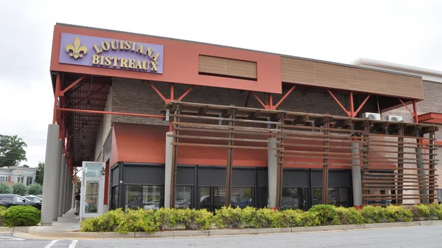Exterior view of Louisiana Bistreaux restaurant with red accents and green landscaping in front.