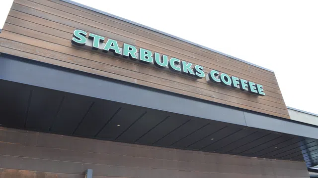 Exterior view of a Starbucks Coffee shop with wooden paneling and green signage on a clear day