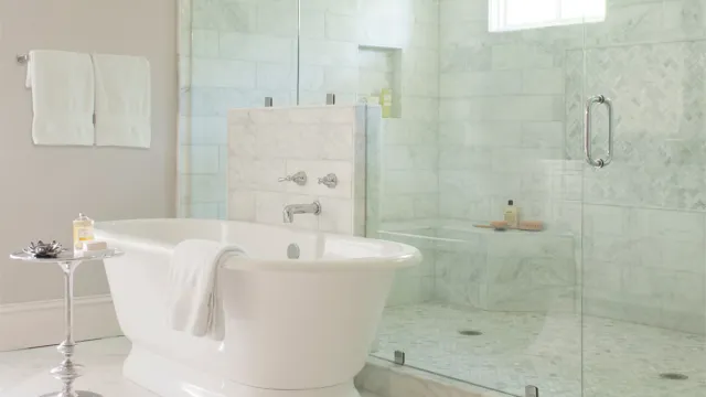 Modern bathroom with white freestanding tub, glass shower enclosure, marble tiles, and chrome fixtures