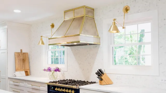Modern kitchen featuring a blue stove, white cabinetry, and stylish gold accents.