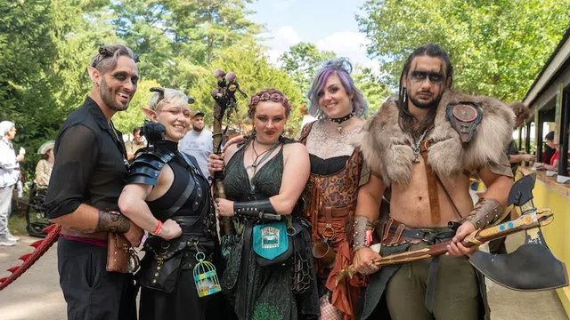 Group of five people in fantasy costumes posing outdoors at a Renaissance or fantasy festival event.