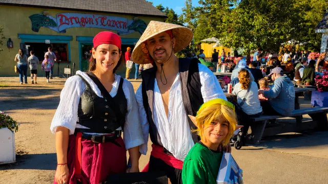 Family in medieval and fantasy costumes posing at a Renaissance fair in front of Dragon's Tavern.