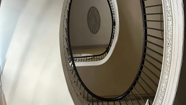 Spiral staircase with ornate white railing and black balusters viewed from below inside a building.