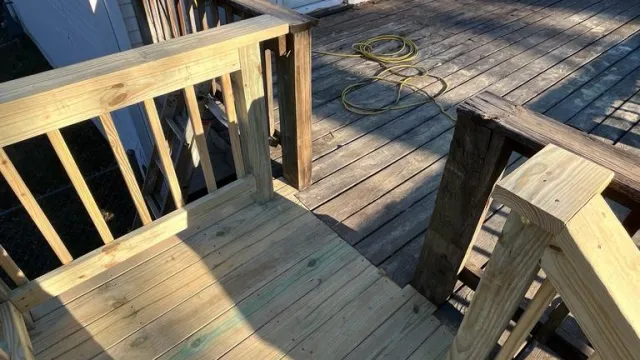 Newly built wooden deck and stairs attached to a house with a sliding glass door and old deck in the background.