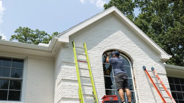 a person on a ladder painting a house