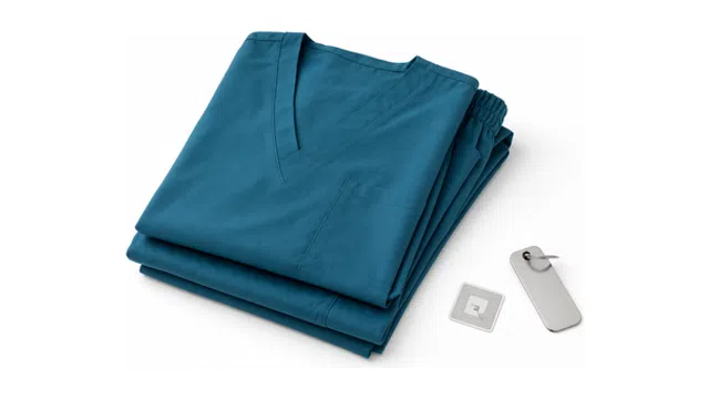 Folded blue medical scrubs with pocket and elastic waistband next to a medical tool on white background