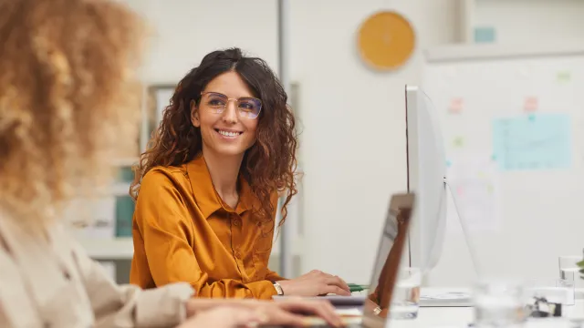 Two professionals working collaboratively in a bright office, focused and engaged in their tasks.