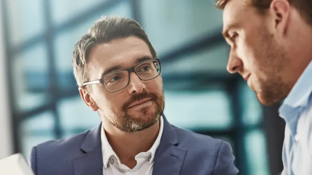 Two business professionals engaged in discussion with a tablet in a modern office setting.