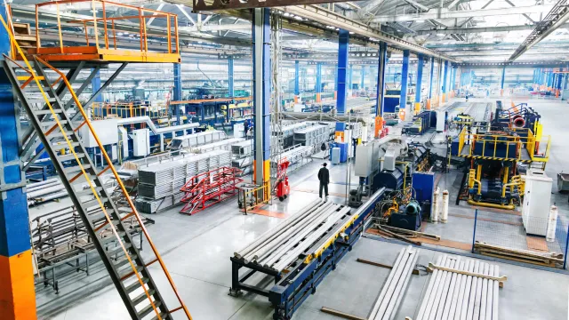 Aerial view of a modern factory interior with machinery and metal products in a spacious layout.
