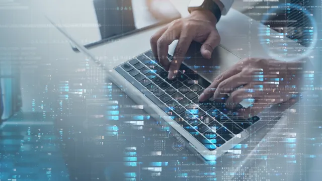 Person typing on a laptop with data visualizations in the background.