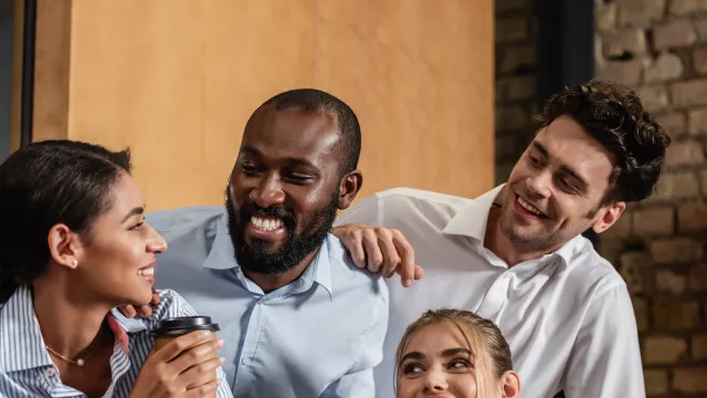 Diverse group of professionals enjoying a casual meeting in a modern office setting.