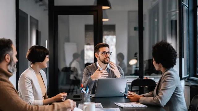 A diverse group of professionals engaged in a collaborative meeting around a conference table.