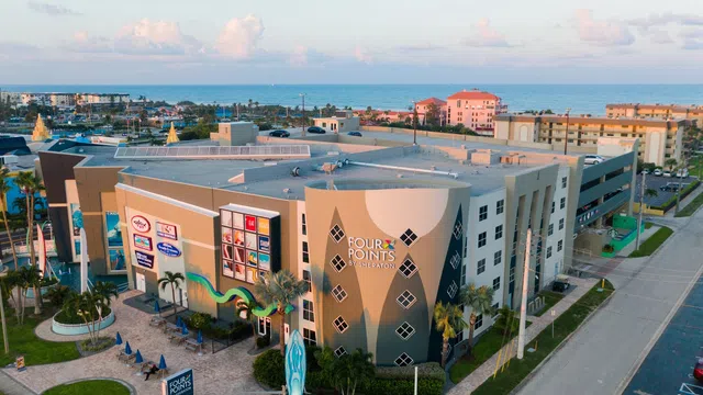 Aerial view of Four Points by Sheraton hotel near ocean with nearby buildings and palm trees during daytime.