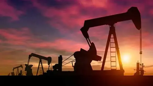 Silhouettes of oil pump jacks at sunset with a colorful sky in the background