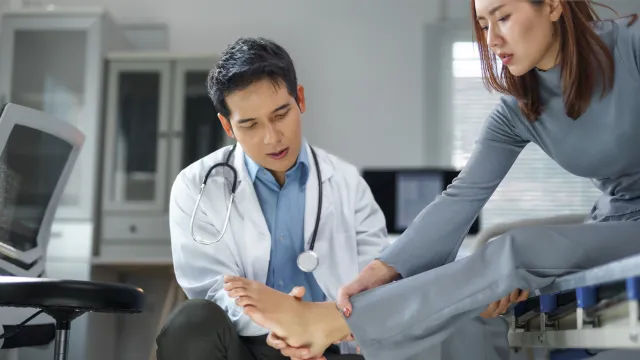 Doctor examining patient’s foot in a medical office focused on foot pain or injury diagnosis.