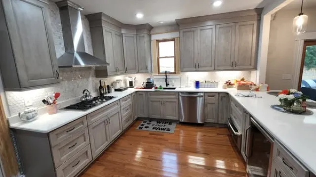 Modern U-shaped kitchen with light wood cabinets, stainless steel appliances, and hardwood flooring.