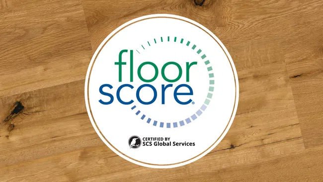 Floor Score certification logo on a wooden floor background indicating indoor air quality compliance.
