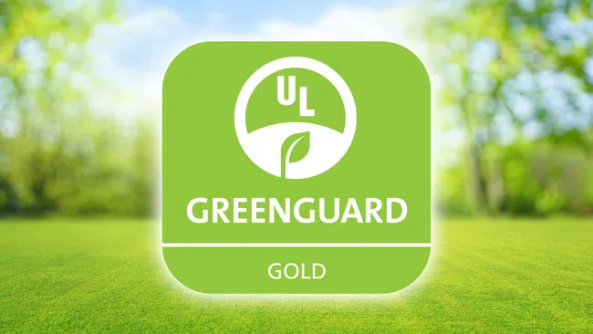 UL GREENGUARD Gold certification logo on a green outdoor background with blurred trees and grass.
