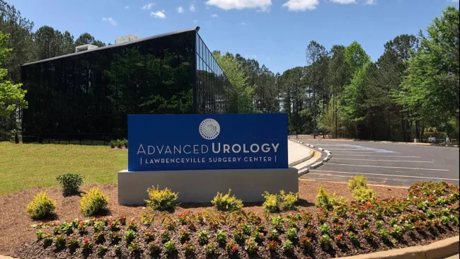Sign for Advanced Urology at Lawrenceville Surgery Center surrounded by greenery and flowers.