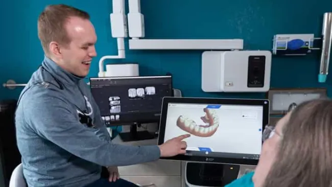 Dentist showing digital 3D dental scan to patient on computer screen in dental clinic
